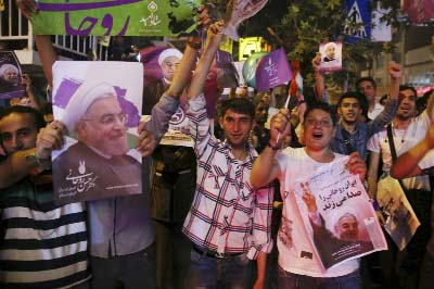 Supporters of Iranian President Hassan Rouhani cheer while holding his posters during a street campaign ahead the May 19 presidential election in downtown Tehran, Iran.