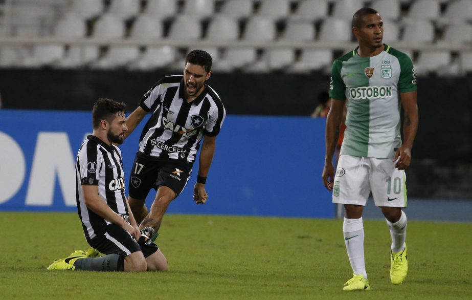 Rodrigo Pimpao of Brazil's Botafogo (kneeling) celebrates with teammate Joao Paulo as Macnelly Berrio of Colombia's Atletico Nacional walks off the field at the end of a Copa Libertadores soccer match at Nilton Santos stadium in Rio de Janeiro, Brazil,