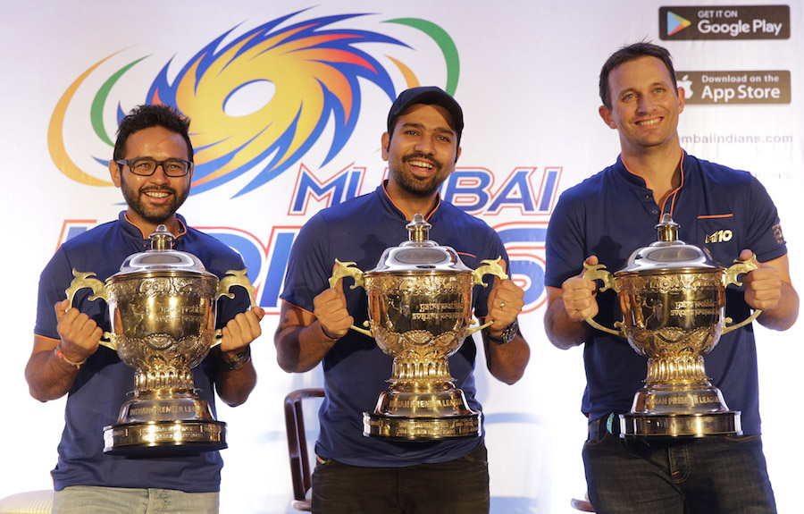 Mumbai Indians captain Rohit Sharma (center) Parthiv Patel (left) and bowling coach Shane Bond pose for a picture with the Indian Premier League (IPL) trophies from last three wins after a press conference after their IPL 2017 win in Mumbai, India on Mond