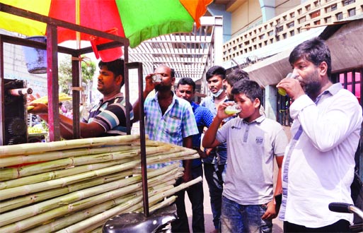 People drinking juice, now on sales in the city streets, to get a bit relief from blistering temperature as heat wave sweeps the country. These juices are being prepared in an unhygienic condition. This photo was taken from the city's Gulistan area on Tu