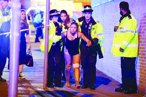 An injured woman is escorted from the arena in Manchester by police after loud bangs were heard at the gig.