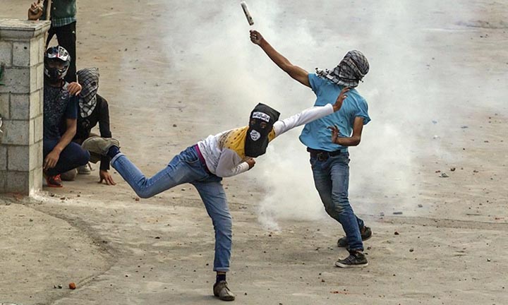 Masked Kashmiri protesters throw exploded tear gas at Indian policemen during a protest in Srinagar, Indian controlled Kashmir on Friday.