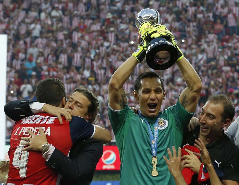Chivas' coach Matias Almeyda is embraced by Chivas' Jair Pereira as goalie Rodolfo Cota holds the trophy as the team celebrates its win over Tigres for the Mexican soccer league championship in Guadalajara, Mexico on Sunday.