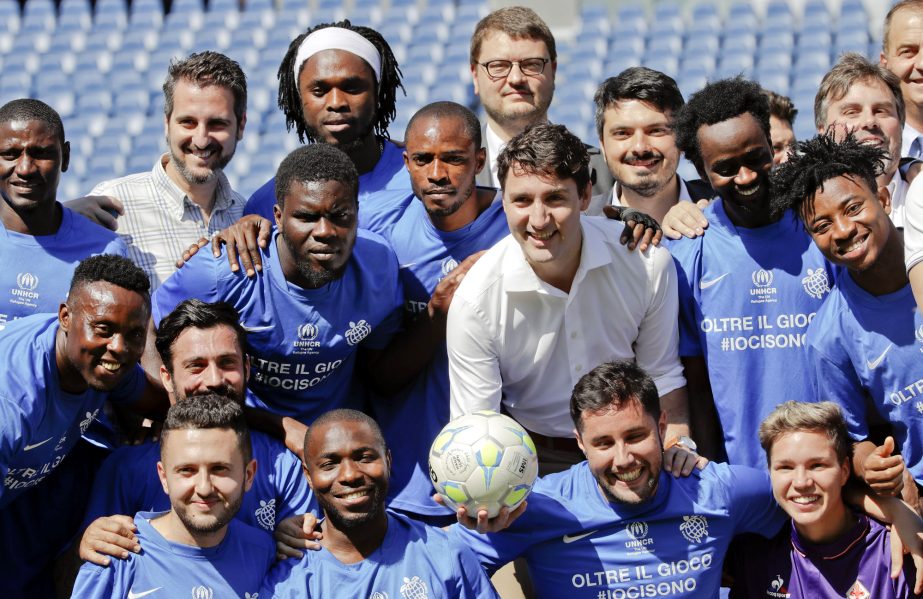 Canadian Prime Minister Justin Trudeau (center right) holds a soccer ball as he poses for a group photo with refugees at a sporting event promoting social integration through soccer, at Rome's Olympic stadium on Monday.