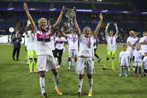 Lyon's Ada Hegerberg (left) and Lyon's Eugenie Le Sommer celebrate with the trophy after the Women's Champions League Final soccer match at the Cardiff City Stadium in Cardiff, Wales on Thursday.