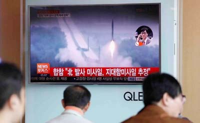 People watch a TV broadcast of a news report on North Korea missile firing..