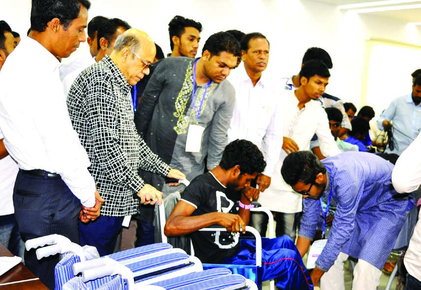 Food Minister Qamrul Islam distributing wheel chairs among the paralysed people at a ceremony organised by different organisations including Aparajeya Bangla at the Jatiya Press Club on Saturday.