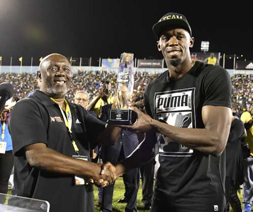 Jamaica's Usain Bolt receives a special award from his coach, Glen Mills, before competing in the "Salute to a Legend" 100 meters during the Racers Grand Prix at the national stadium in Kingston, Jamaica on Saturday. Bolt started his final season with