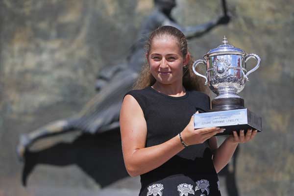 Latvia's Jelena Ostapenko holds the trophy as she poses in front of a statue of French tennis star Suzanne Lenglen during a photo call one day after winning the women's final match of the French Open tennis tournament against Romania's Simona Halep in