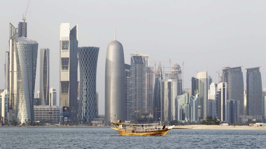 Photo shows a traditional dhow floats in the Corniche Bay of Doha, Qatar, with tall buildings of the financial district in the background.