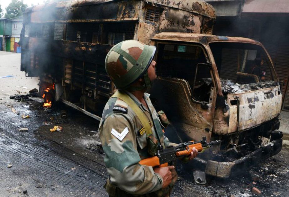 Photo shows an Indian soldier patrolling next to a burned-out vehicle after clashes in Darjeeling.