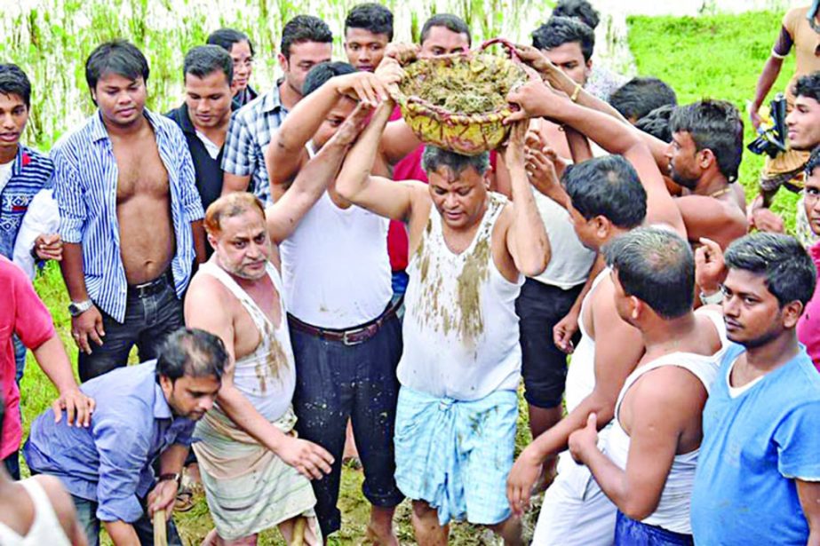 Former minister and publicity secretary of Awami League Dr Hasan Mahmud MP carrying mud on his head to repair a damaged road at Ranguina on Sunday.