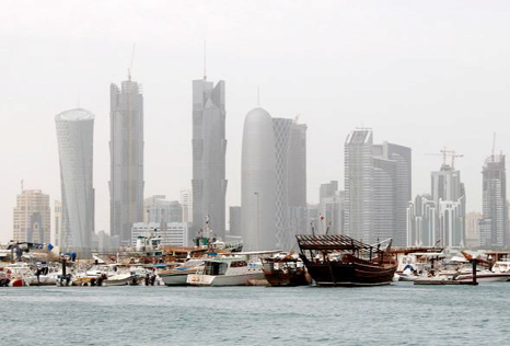 A traditional wooden fishing Dhow is seen in port near modern glass and steel buildings on the Doha skyline, Qatar