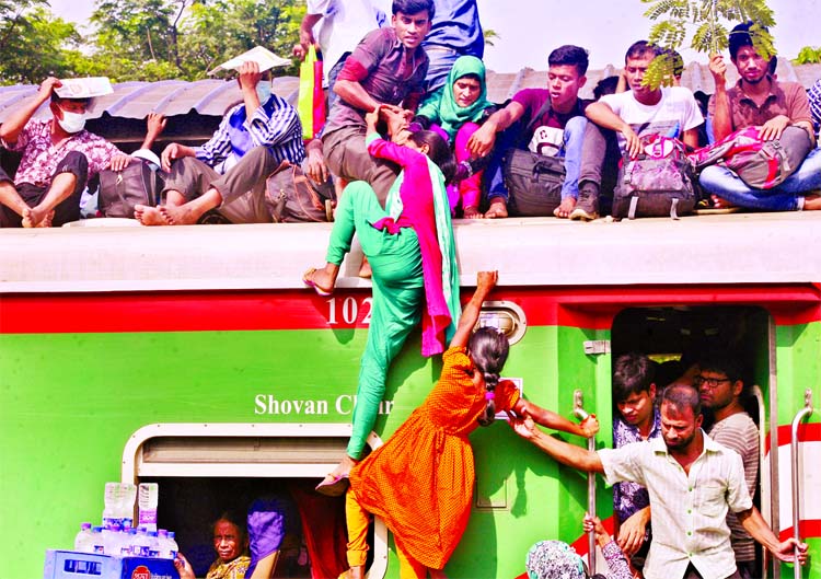 Eid home-bound women passengers are trying hard to ride the rooftop of the train taking risk of life at the Biman Bandar Railway Station on Friday.