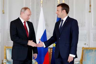 French President Emmanuel Macron shakes hands Russian President Vladimir Putin (L) at the Chateau de Versailles as they meet for talks before the opening of an exhibition marking 300 years of diplomatic ties between the two countries in Versailles, France