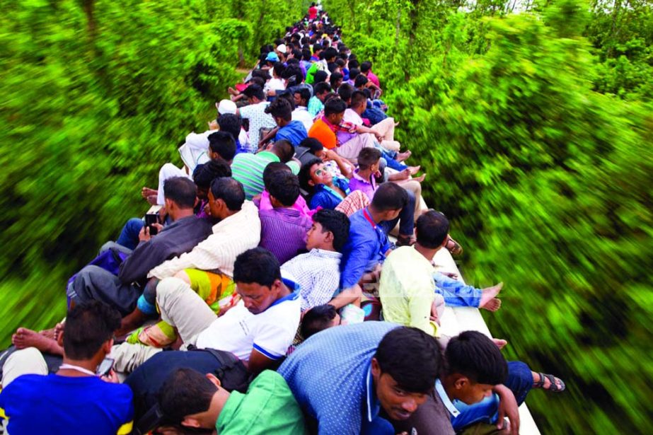 Hundreds of people of all ages ride the rooftop of a train, risking their lives left for village homes to celebrate Eid. This photo was taken from the outskirts of the city on Saturday.