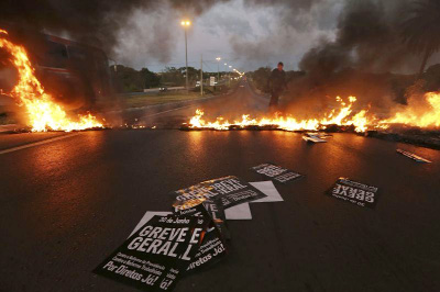 Military policemen clear a flaming barricade on an access highway to Brasilia, Brazil early on Friday.