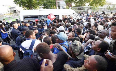 Migrants line up as they wait to be evacuated from a makeshift street camp, in Paris, France on Friday.