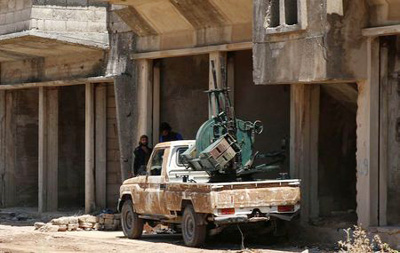 Free Syrian Army fighter stand near an anti-aircraft machine gun in Quneitra, Syria