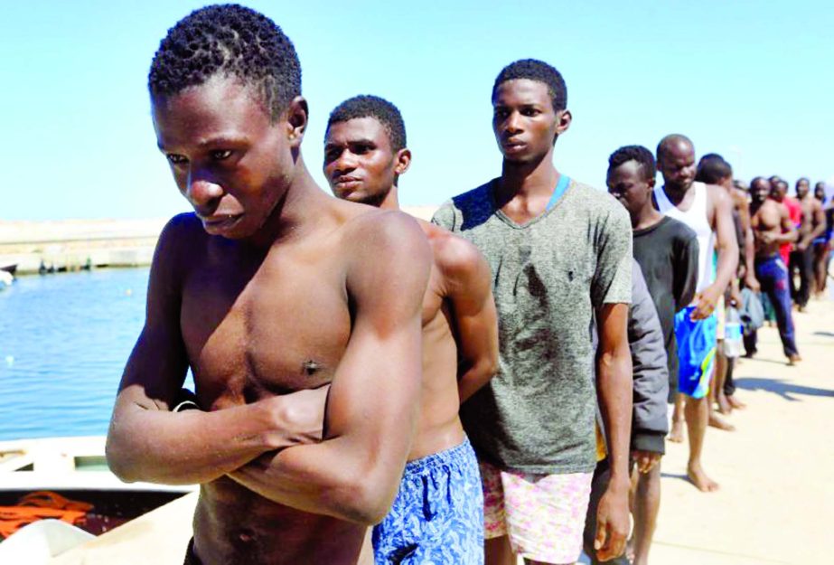 Migrants rescued by Libya's coastguard off the town of Garabulli on July 8, 2017 walk towards a detention center.