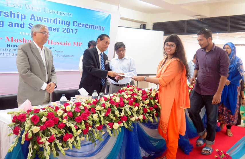 H N Ashequr Rahman MP, Member, Board of Trustees, East West University handing over scholarship papers to the students of the university at a ceremony held on last Wednesday at its Aftab Nagar Campus in the capital.