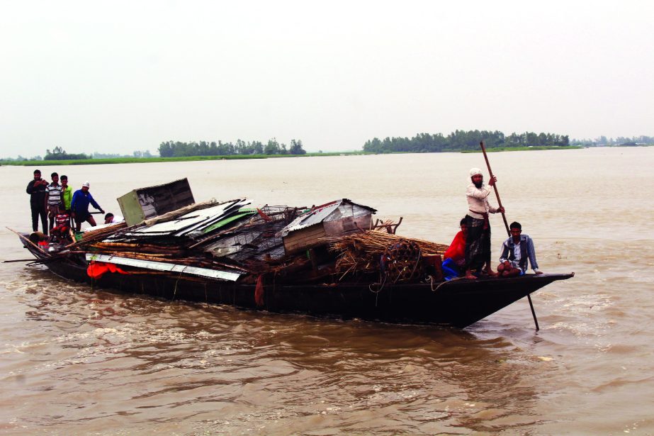 BOGRA: A flood affected family with his households including materials of the house going to safer place from char areas . This picture was taken from the Jamuna River at Sariakandi yesterday.