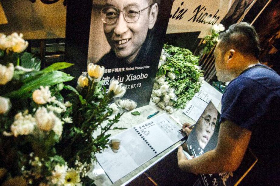 A man writes a message and holds a portrait outside the Chinese Liaison Office of Hong Kong after the death of Chinese Nobel laureate Liu Xiaobo, in Hong Kong on Friday.
