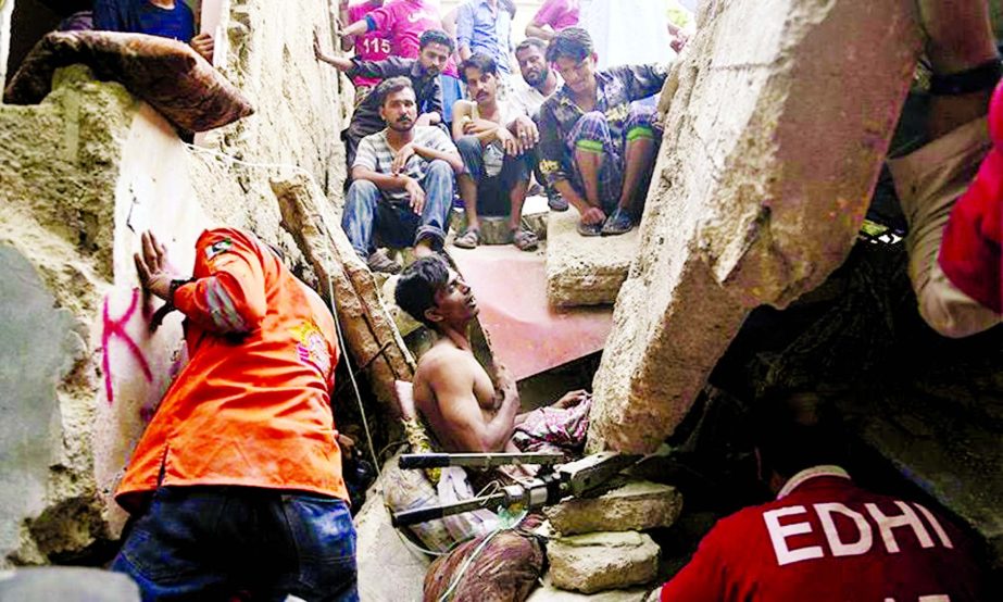 Volunteers try to rescue a trapped resident in Karachi on Tuesday.