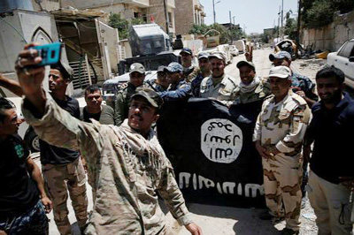 Members of the Iraqi Army's 9th Armoured Division are photographed with an Islamic State flag, claimed after fighting with Islamic State militants in western Mosul, Iraq.