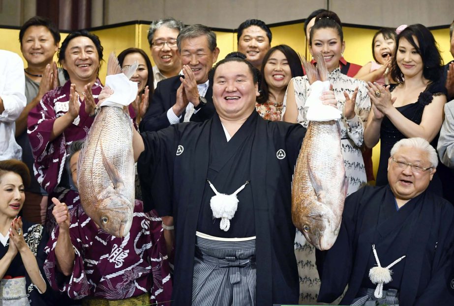 In this Sunday, July 23, 2017 photo, Mongolian grand champion Hakuho (center) celebrates after he won the Nagoya Grand Sumo Tournament in Nagoya, Aichi prefecture, central Japan. Hakuho won the 39th career title.