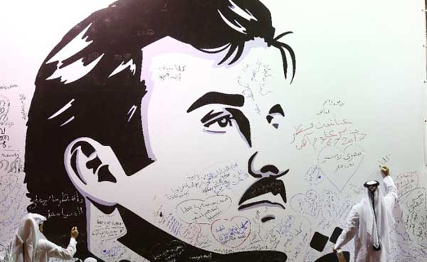 A man writes on a wall bearing a portrait of Qatar's Emir Sheikh Tamim bin Hamad Al Thani that has become a symbol of Qatari resistance in the Gulf crisis in Doha