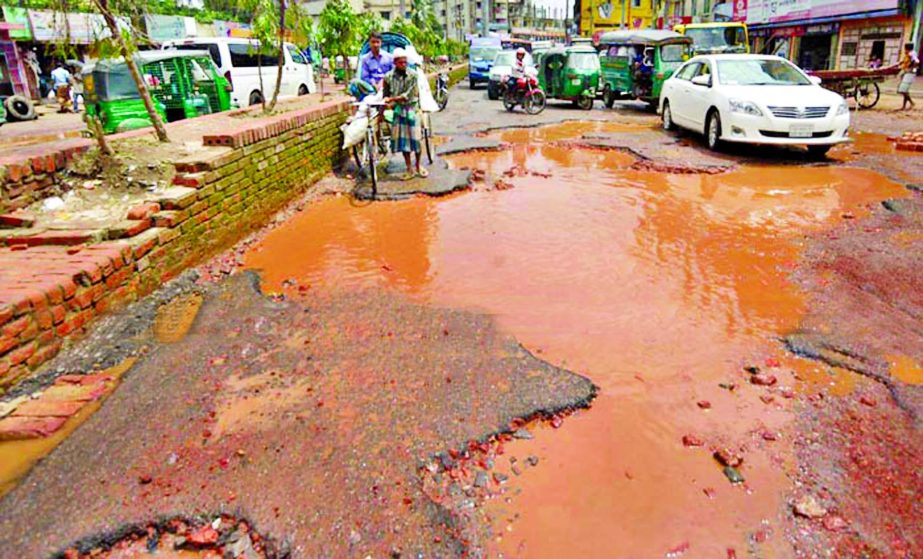 Several potholes and cracks developed on the main thoroughfare at Arakan area in Port city with the recession of floodwaters, causing sufferings to commuters. This photo was taken on Friday.