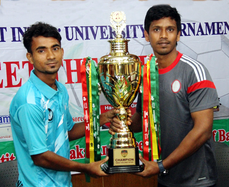 Mainul Abedin (left) of Fareast International University and Bashiruddin of Green University pose with the championship trophy of the Walton 1st Inter-University Football Tournament at the conference room of the Bangabandhu National Stadium on Wednesday.