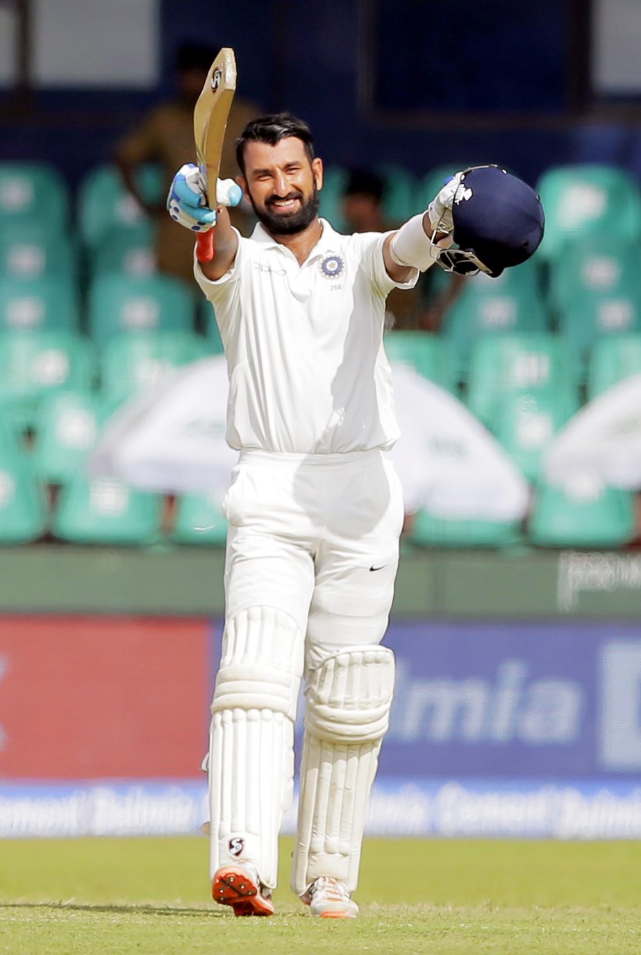 India's Cheteshwar Pujara raises his bat and helmet to celebrate scoring a century during their second cricket test match against Sri Lanka in Colombo, Sri Lanka, Thursday.