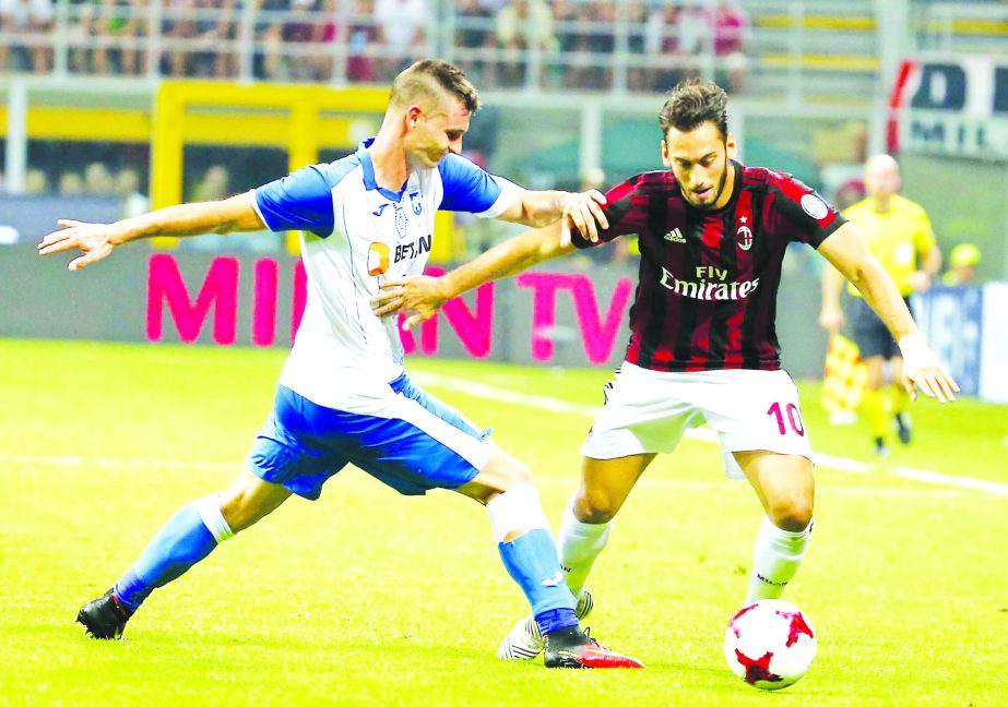 AC Milan's Hakan Calhanoglu, (right) challenges for the ball with U Craiova's Hrvoje Spahija during an Europa League third qualifying round, second leg, soccer match at the San Siro stadium in Milan, Italy on Thursday.