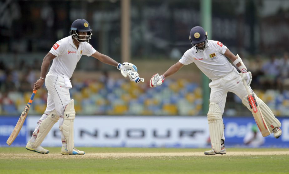 Sri Lankan batsmen Dimuth Karunaratne (left) and Kusal Mendis stretch their arms to cheer each other during their second cricket test match against India in Colombo, Sri Lanka on Saturday.