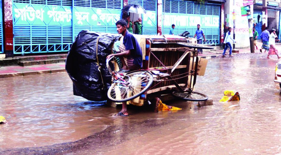 A rickshaw vanpuller struggling hard to pullout it from the hidden pothole being covered with rain waters. This photo was taken from Malibagh-Chowdhurypara South Point School and College in city on Saturday.