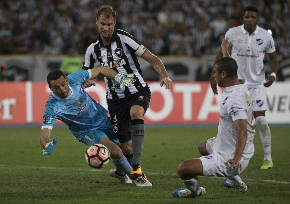 Goalkeeper Esteban Conde of Uruguay's Nacional blocks an attempt to score by Joel Carli of Brazil's Botafogo (center) during a Copa Libertadores soccer match in Rio de Janeiro, Brazil on Thursday.