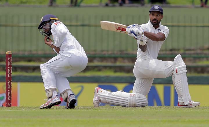 Sri Lanka's Kusal Mendis (left) reacts after a shot played by India's Shikhar Dhawan, right, during the first day's play of their third cricket test match in Pallekele, Sri Lanka on Saturday.