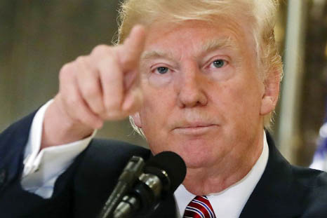 President Donald Trump points to members of the media as he answers questions in the lobby of Trump Tower in New York.