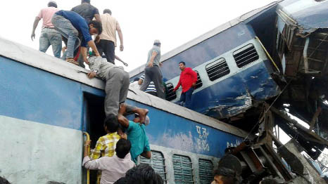 Rescue workers and onlookers stand next to derailed coaches of a passenger train at the site of an accident in Khatauli, in the northern state of Uttar Pradesh, India on Sunday.