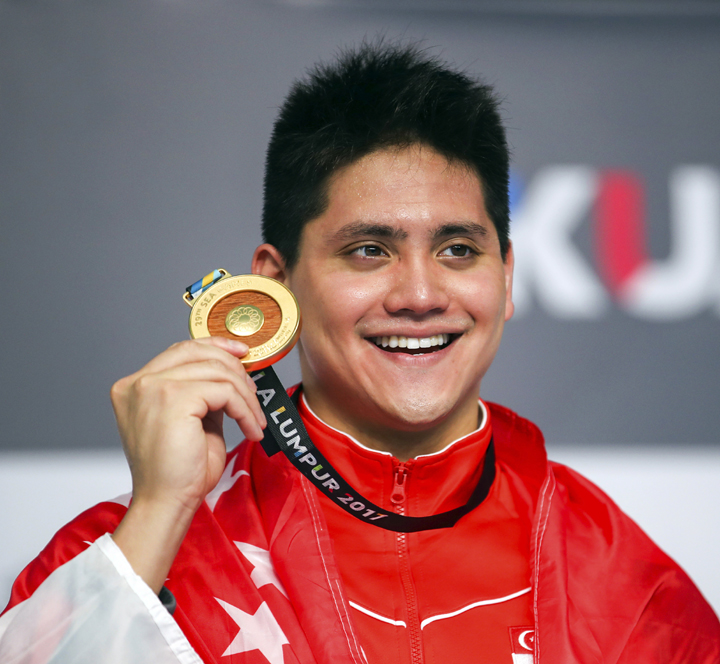 Singapore's Joseph Schooling smiles with his medal after winning the Men's 50M Butterfly Swimming final of the 29th South East Asian Games in Kuala Lumpur, Malaysia on Monday.