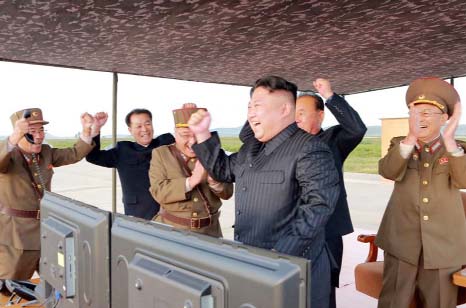 Photo shows North Korean leader Kim Jong Un, (centre) celebrates what was said to be the test launch of an intermediate range Hwasong-12 missile at an undisclosed location in North Korea.