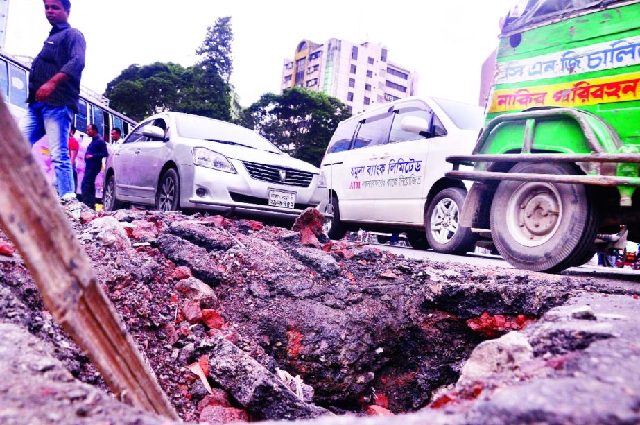 Rising number of big potholes developed in the capital Dhaka's different roads is putting drivers at danger. This photo was taken from in front of Bangladesh Shilpa Bank Bhaban in Motijheel area on Sunday.