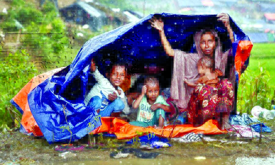 Holding only a tarpaulin a Rohingya woman along with her four children is trying to protect themselves from the rain at Balukhali camp in Teknaf Upazila of Cox's Bazar district. This photo was taken on Monday.