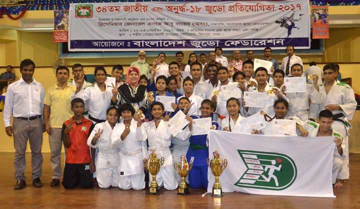 Members of BKSP team, who became champion in Under-16 two-day long Judo Competition pose for photo with the trophy and guests at the Shaheed Suhrawardy Indoor stadium in Mirpur on Saturday.