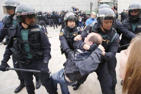 Spanish police drag a man outside a polling station where Catalonia's president was supposed to vote in the region's