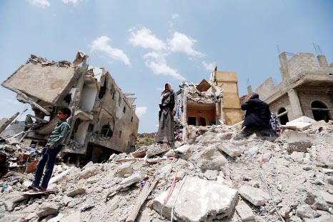 Yemeni men stand on the debris of a house, hit in an air strike on a residential district, in the capital Sanaa.