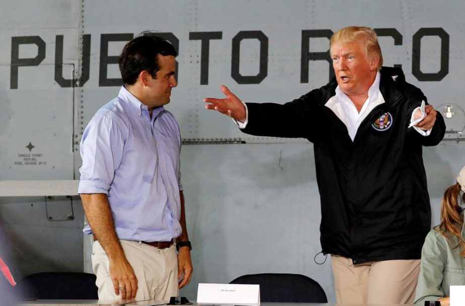 President Donald Trump talks with Puerto Rico Governor Ricardo RossellÃ³ as they take their seats for a briefing on hurricane relief efforts in a hangar at Muniz Air National Guard Base in Carolina, Puerto Rico, on Tuesday.