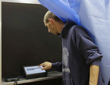 Carlo Andrea Carnevale Ricci, president of a voting section, checks the electronic voting operation system at the Berchet School polling station, in Milan, Italy on Saturday.